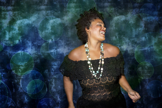 Frau in schwarzem Spitzenkleid vor blau-grünem Hintergrund. | © Jazzclub Schwäbisch Hall e.V.