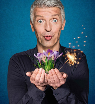 Künstler hält einen Strauß Krokusse sowie eine Wunderkerze in der Hand