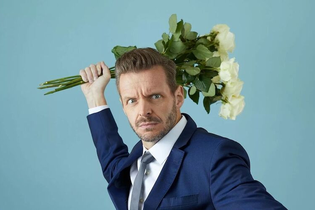 Ein Mann in einem blauen Anzug hält einen Strauß weißer Rosen in einer dramatischen Pose vor einem blauen Hintergrund. | © Konzertkreis Triangel Compagnia Compostelli e.V.