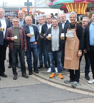 Gruppenbild Männer mit Bierkrug vor dem Karusell