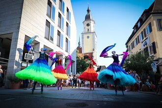 Farbenfrohe Stelzenläufer tanzen auf einer Straße | © Stadtverwaltung Crailsheim