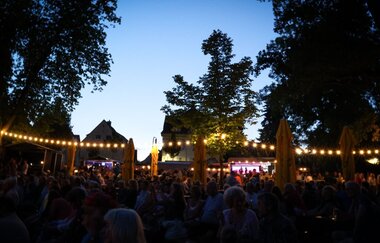 Lichterketten zwischen Bäumen, Menschen sitzen auf Bänken | © Stadtverwaltung Crailsheim