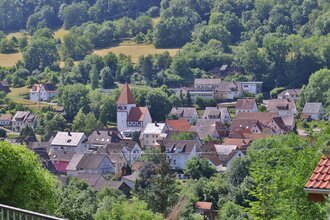 Eine Luftaufnahme von der Ortschaft Morsbach mit Häusern, Kirche und Wald | © Touristikgemeinschaft Hohenlohe e. V. | Andi Schmid