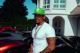 Luciano steht vor einem weißen Haus, neben sich zwei Autos.