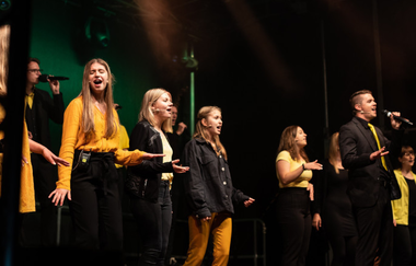 Gemischter Chor auf der Bühne bei schöner Beleuchtung.