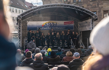 Bühne auf dem Marktplatz. Im Vordergrund Besucher, im Hintergrund das Rathaus und das Käthchenhaus.