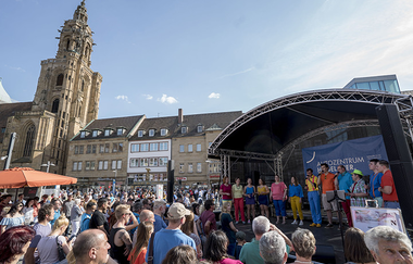 Bühne auf dem Marktplatz, im Hintergrund der Turm der Kilianskirche. Viele Zuschauer vor der Bühne.