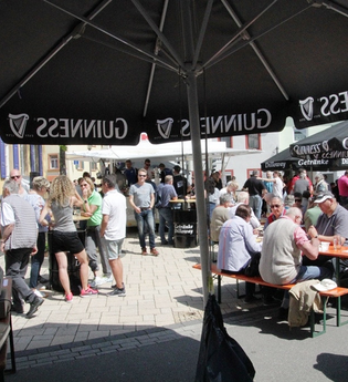 Menschen auf Bierbänken und am Bierstand