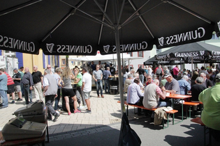 Menschen auf Bierbänken und am Bierstand