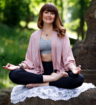 Sonja Lanig sitzt in einer Yoga-Pose im Garten | © Sonja Lanig