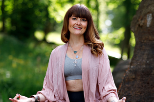 Sonja Lanig sitzt in einer Yoga-Pose im Garten | © Sonja Lanig