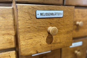 Schublade aus Holz, die geöffnet ist mit einem Schild, auf dem Melissenblätter