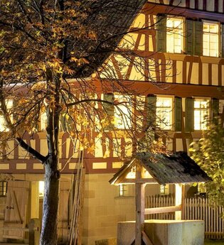 Ein altes Bauernhaus mit Fachwerk ist beleuchtet. Es ist Nacht. | © Hohenloher Freilandmuseum