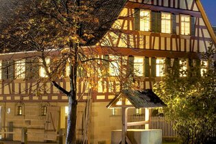 Ein altes Bauernhaus mit Fachwerk ist beleuchtet. Es ist Nacht. | © Hohenloher Freilandmuseum