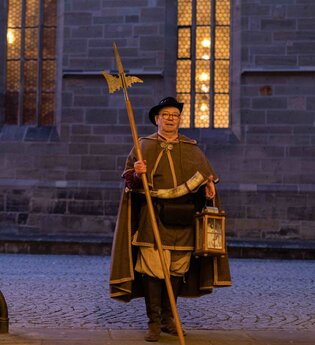 Mit Hellebarde und Laterne in der Hand steht der Nachtwächter in historischer Tracht für die Stadtführung am Tor zum Öhringer Schloss bereit | © Touristikgemeinschaft Hohenlohe e.V. | Stadt Öhringen