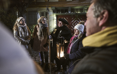 Ein Gruppe Menschen hört gespannt einem Erzähler zu. Es ist Nacht. Der Gästeführer ist als Nachtwächter verkleidet, trägt eine Hellbarde und eine Laterne. | © Tourimia Tourismus GmbH