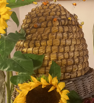 alter Bienenkorb aus Stroh mit Sonnenblumen | © Petra Natzkowski