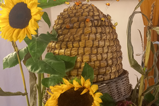 alter Bienenkorb aus Stroh mit Sonnenblumen | © Petra Natzkowski