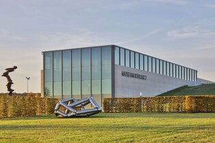 Das moderne Gebäude ist halb in die Erde gebaut, davor stehen zwei Skulpturen | © Touristikgemeinschaft Hohenlohe e. V. | Andi Schmid