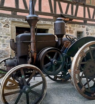 Alter Traktor (Oldtimer-Traktor) steht vor dem Steigengasthaus, einem Fachwerkhaus.