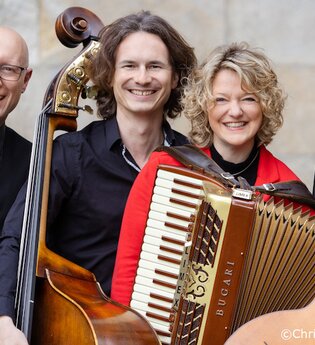 Vier Musiker mit Instrumenten, darunter ein Akkordeon, Kontrabass, Gitarre und Trommel, lächeln in die Kamera. | © Kultur- und Sportamt Stadt Bietigheim-Bissingen