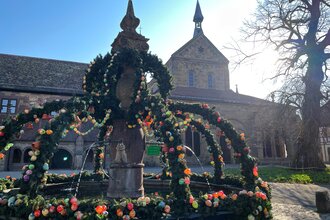 Geschmückter Osterbrunnen im Klosterhof im Hintergrund die Klosterkirche bei Sonnenschein | © Stadt Maulbronn