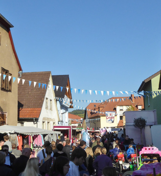Viele Menschen bummeln durch die Rauenberger Innenstadt, zwischen den Häusern spannen Girlanden und an den Straßenrändern reihen sich links und rechts Imbissbuden und Verkaufszelte | © Landratsamt Rhein-Neckar-Kreis