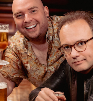 Zwei Männer in einer Bar, einer hält ein Bierglas, der andere trägt eine Brille und eine Lederjacke. | © Kultur- und Sportamt Stadt Bietigheim-Bissingen