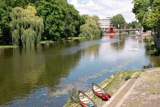 4 Kanus liegen auf der letzten breiten Stufe direkt am Neckar. In weiter Ferne ist das rote one man house erkennbar, auf der gegenüberliegenden Seite säumen hohe Bäume das Ufer
