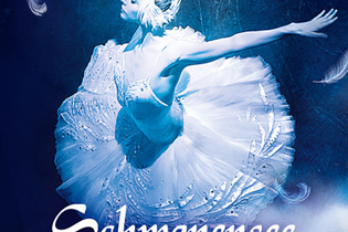 Ballerina in weißem Tutu tanzt auf der Bühne, umgeben von blauen Lichteffekten und Federn. | © PTF GmbH / Konzertagentur Friedmann