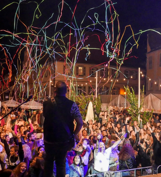 Eine Band spielt Musik auf dem Marktplatz, Luftschlangen schießen in die Luft und rieselt auf die Menschenmenge runter. | © The Cuba Brothers
