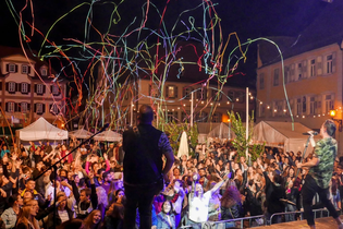 Eine Band spielt Musik auf dem Marktplatz, Luftschlangen schießen in die Luft und rieselt auf die Menschenmenge runter. | © The Cuba Brothers