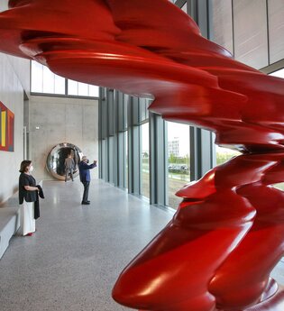 Zwei Besucher bewundern eine rote Skulptur und genießen den Ausblick ins Grüne | © Touristikgemeinschaft Hohenlohe e. V. | Firma Würth