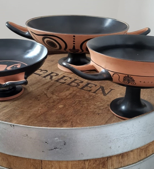 Drei Repliken von griechischen Trinkschalen auf einen Weinfass.