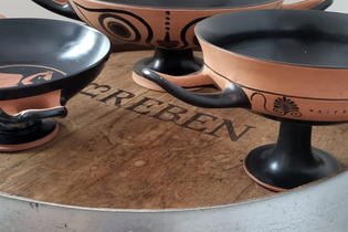 Drei Repliken von griechischen Trinkschalen auf einen Weinfass.