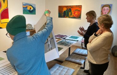 Das Bild zeigt drei Personen, die die Linioldrucke anschauen und überlegen, welche Drucke zur aktuellen Ausstellung passen. | © 13 Reben Bio-Weingut