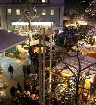 In weihnachtlicher Lichteratmosphäre stehen viele Besucher auf einem Marktplatz und sprechen miteinander. | © Gemeinde Blaufelden