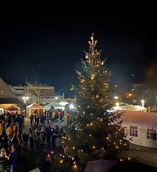 Weihnachtsbaum mit Verkaufsständen, im Hintergrund Kirchturm, Mühlbach