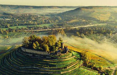 Drohnenaufnahme der Burgruine Weibertreu im Morgennebel. Aussicht über Weinsberger Tal mit dem Naturpark Schwäbisch-Fränkischer Wald im Hintergrund. | © Touristikgemeinschaft HeilbronnerLand