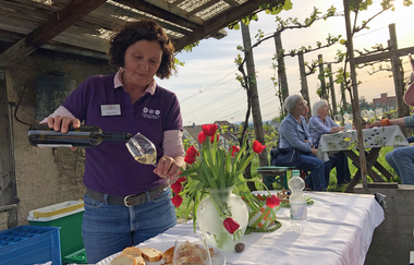 Die Weinerlebnisführerin schenkt Wein in ein Glas am Wengerthaus in Asperg mit Tulpenstrauß auf dem dekorierten Tisch | © Daisy Knisel