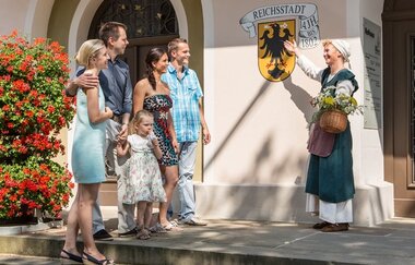 Gästeführerin im historischen Gewand mit Besuchergruppe an der Rathaustreppe | © Stadt Bad Wimpfen