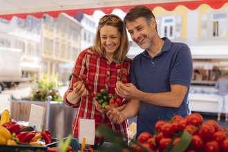Eine Frau und ein Mann schauen sich Tomaten auf dem Wochenmarkt an | © PHILIPPREINHARD.COM