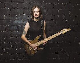 Yasi Hofer ist vor schwarzem Hintergrund mit Gitarre zu sehen | © Kulturforum Brackenheim e. V.