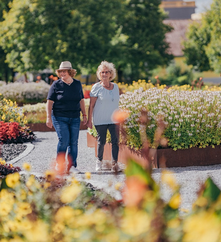 Zwei Frauen spazieren durch das Feuerbeet und bewundern die Blumenpracht der Beete. | © Stadt Bad Rappenau I Chris Frumolt