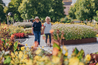 Zwei Frauen spazieren durch das Feuerbeet und bewundern die Blumenpracht der Beete. | © Stadt Bad Rappenau I Chris Frumolt