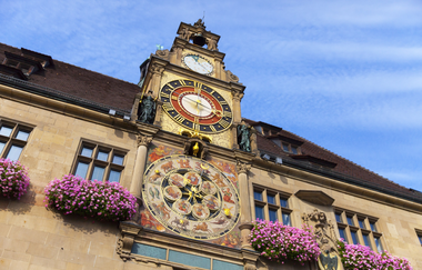Das Bild zeigt einen Teil des Rathauses von  schräg unten fotografiert. Mittig ist die historische Kunstuhr zu sehen. Sie ist dreiteilig und besteht oben aus der Monduhr in der Mitte aus der 12-Stunden-Uhr und unten aus der Tierkreiszeichenuhr | © Heilbronn Marketing GmbH