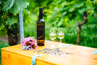 Weinflasche und zwei Weingläser stehen auf einer Holzkiste mit der Aufschrift WEIN GENUSS+ | © Biohof Döbler