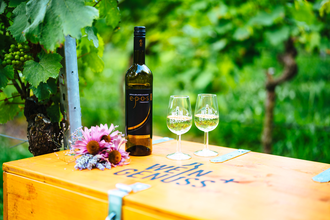 Weinflasche und zwei Weingläser stehen auf einer Holzkiste mit der Aufschrift WEIN GENUSS+ | © Biohof Döbler