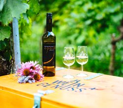 Weinflasche und zwei Weingläser stehen auf einer Holzkiste mit der Aufschrift WEIN GENUSS+ | © Biohof Döbler