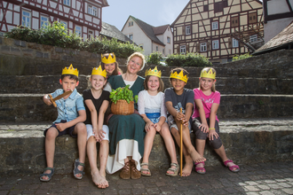 Kindergruppe mit selbst gebastelten Kronen und Gästeführerin | © Stadt Bad Wimpfen